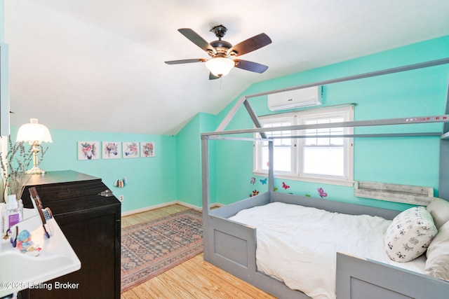 bedroom with vaulted ceiling, light hardwood / wood-style flooring, an AC wall unit, and ceiling fan