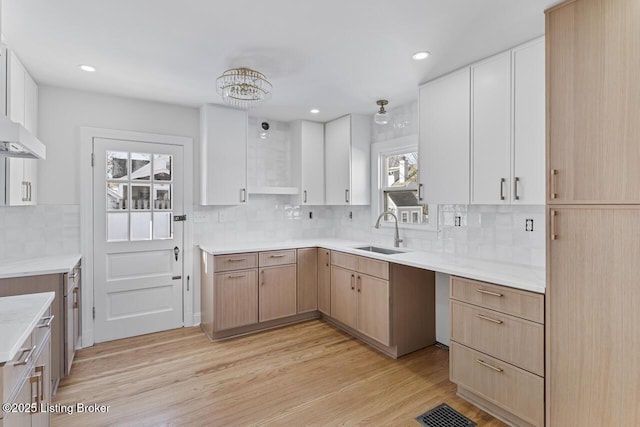 kitchen featuring sink, light hardwood / wood-style floors, white cabinetry, and a healthy amount of sunlight