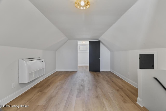 additional living space featuring light hardwood / wood-style floors, heating unit, and vaulted ceiling