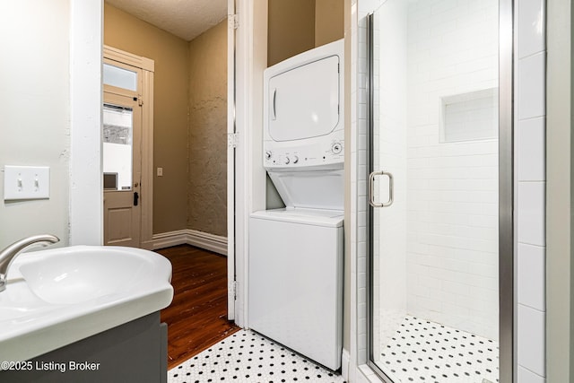 laundry room featuring sink, a textured ceiling, and stacked washer and dryer