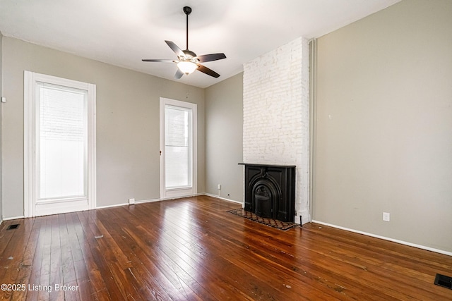 unfurnished living room featuring ceiling fan, a fireplace, and dark hardwood / wood-style flooring