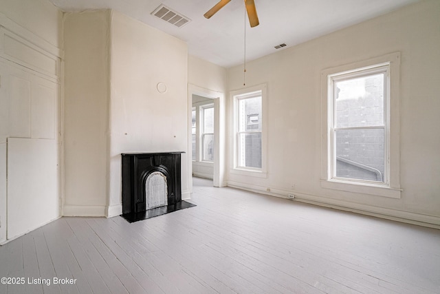 unfurnished living room featuring plenty of natural light, light wood-type flooring, and ceiling fan