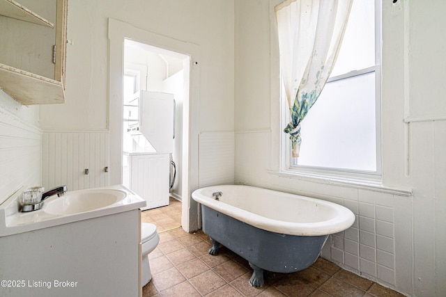 bathroom featuring toilet, a tub to relax in, tile patterned floors, and vanity