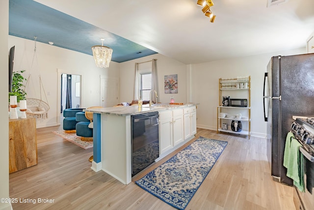 kitchen with sink, white cabinetry, hanging light fixtures, black appliances, and light hardwood / wood-style floors