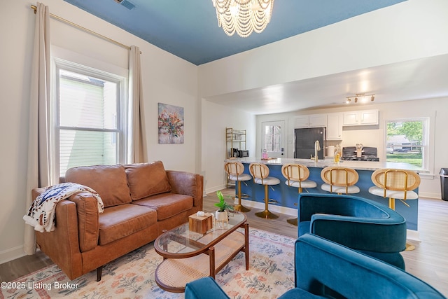 living room featuring a healthy amount of sunlight, a chandelier, and light wood-type flooring