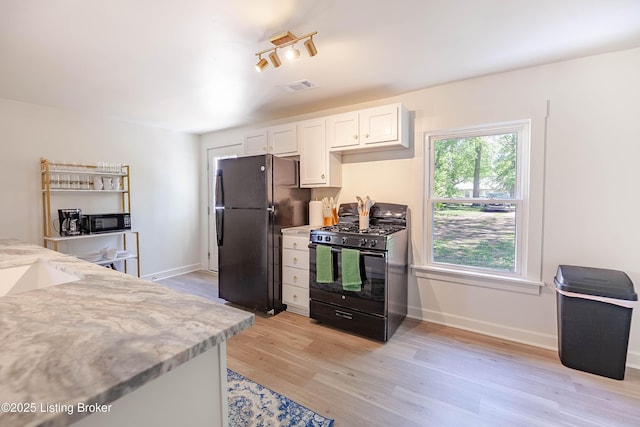 kitchen featuring white cabinetry, light stone countertops, light hardwood / wood-style flooring, and black appliances