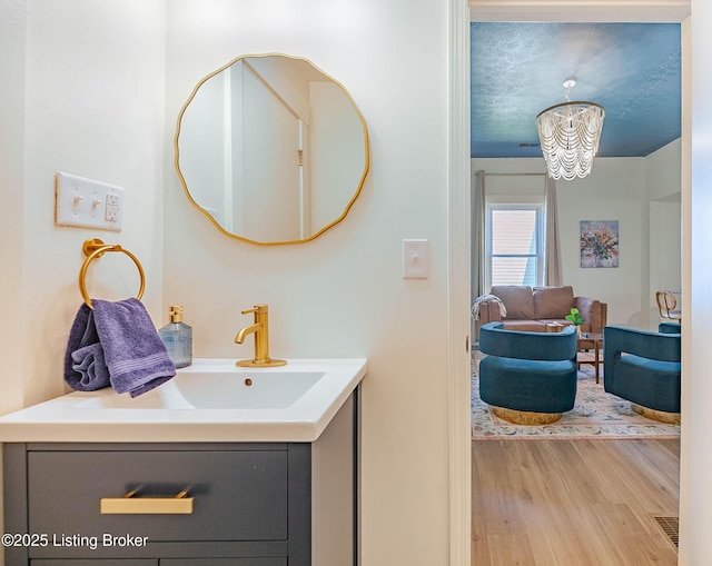 bathroom with vanity, hardwood / wood-style floors, and a notable chandelier