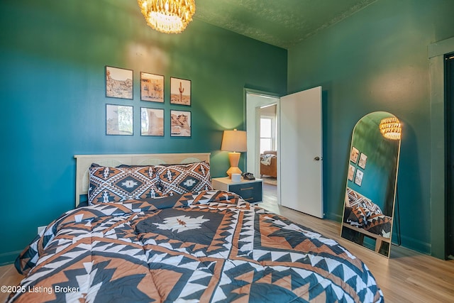 bedroom featuring wood-type flooring, a textured ceiling, and a notable chandelier