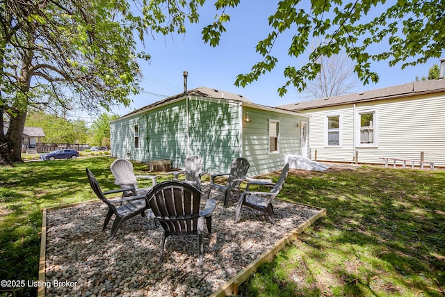 back of house with a fire pit and a lawn