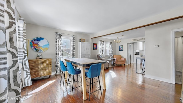 dining area with hardwood / wood-style flooring and an inviting chandelier