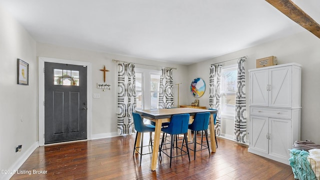 dining area featuring beamed ceiling, a healthy amount of sunlight, and dark hardwood / wood-style floors