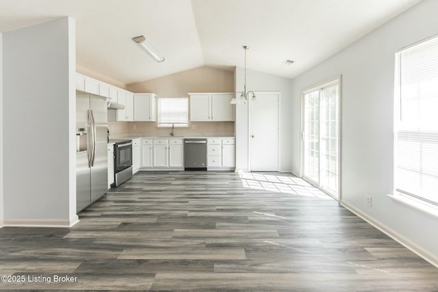 kitchen with appliances with stainless steel finishes, lofted ceiling, white cabinetry, sink, and hanging light fixtures