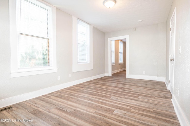 spare room featuring a healthy amount of sunlight and light hardwood / wood-style floors