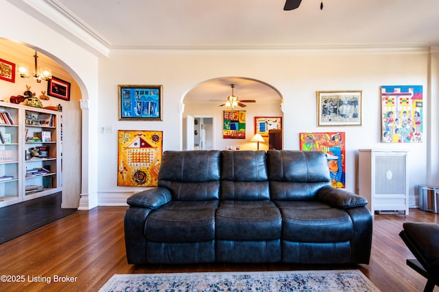 living room featuring ornamental molding, dark wood-type flooring, and ceiling fan with notable chandelier