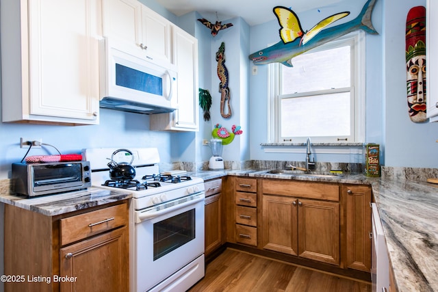 kitchen featuring light stone counters, sink, white appliances, and light hardwood / wood-style floors