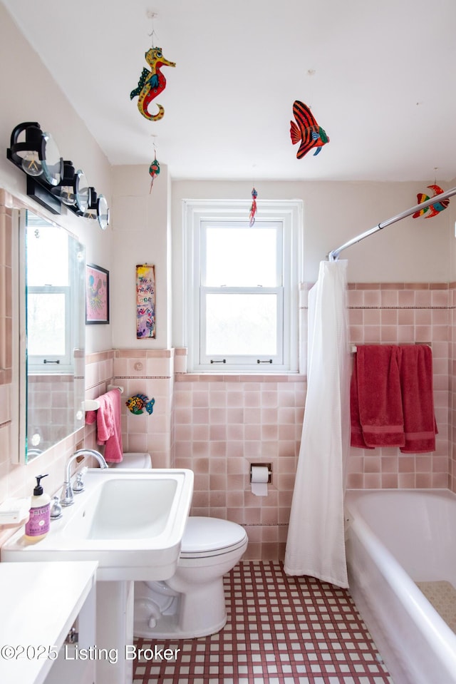 full bathroom with shower / bath combo, sink, tile walls, and toilet