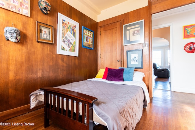 bedroom with wood-type flooring and wooden walls