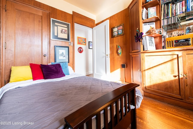 bedroom featuring wooden walls and light hardwood / wood-style flooring