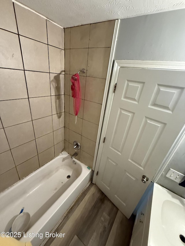 bathroom featuring wood-type flooring, a textured ceiling, tiled shower / bath combo, and vanity