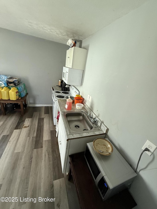 kitchen with white appliances, white cabinets, sink, and wood-type flooring