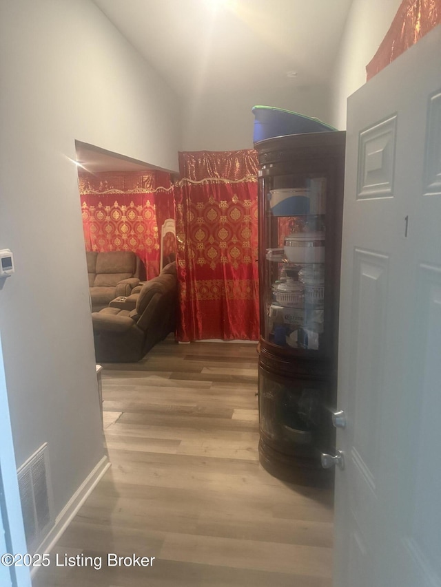 hallway with hardwood / wood-style flooring and vaulted ceiling