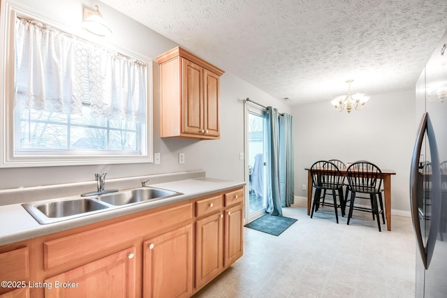 kitchen featuring sink, a wealth of natural light, stainless steel refrigerator, and a textured ceiling