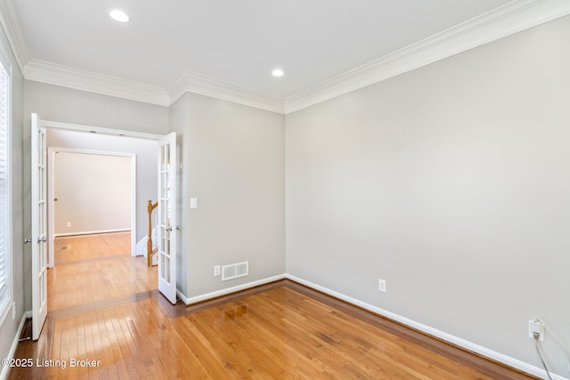 empty room with crown molding and light hardwood / wood-style floors