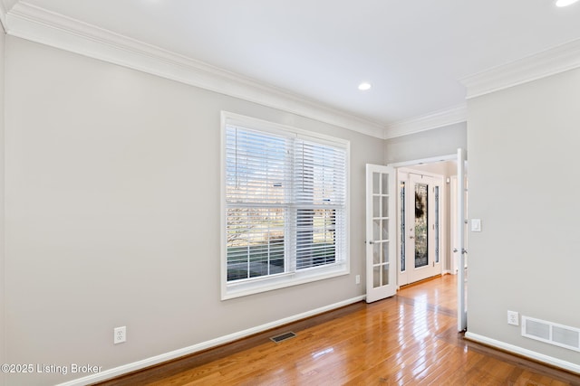 empty room featuring crown molding, hardwood / wood-style flooring, and french doors