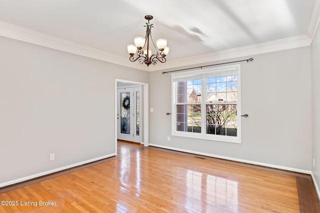 empty room with hardwood / wood-style floors, a notable chandelier, and ornamental molding