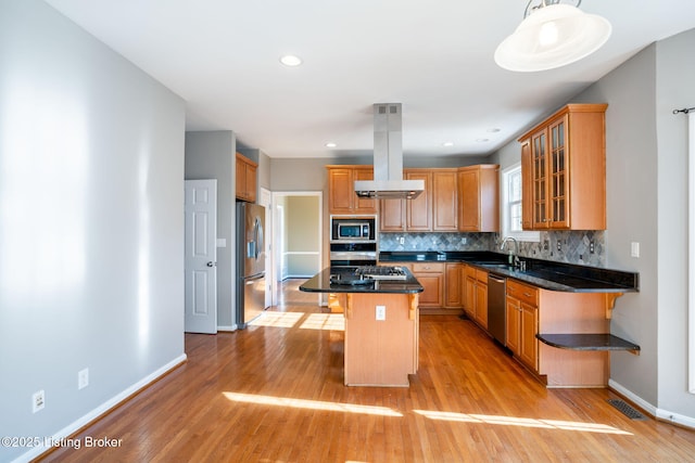 kitchen featuring appliances with stainless steel finishes, island exhaust hood, sink, a kitchen island, and a breakfast bar area