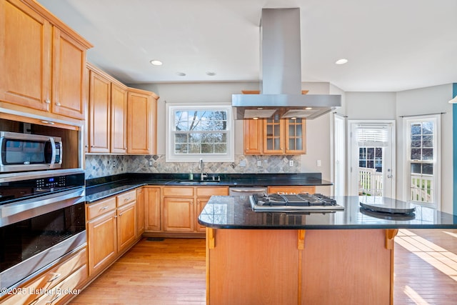 kitchen with sink, a kitchen island, island range hood, a breakfast bar area, and stainless steel appliances