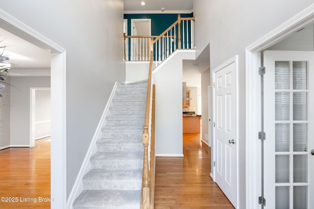 stairs with hardwood / wood-style floors and ornamental molding