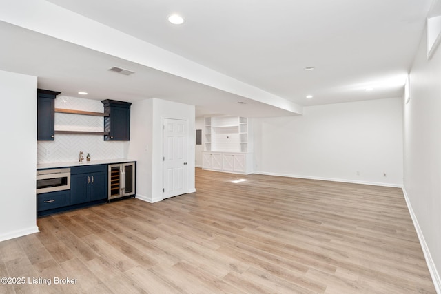 interior space with built in features, light hardwood / wood-style floors, wine cooler, and bar