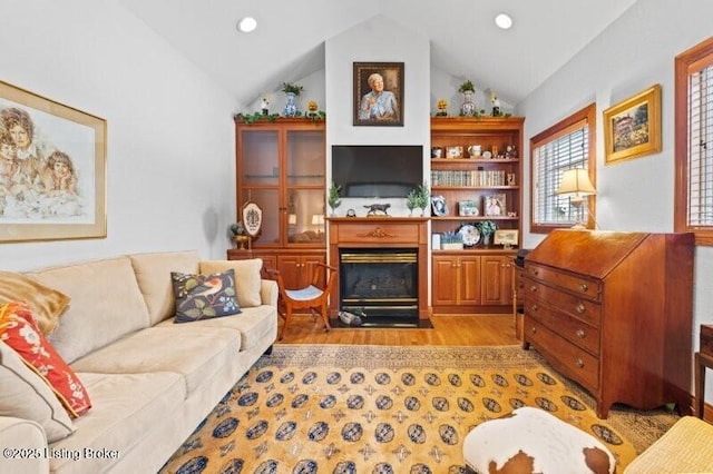 living area featuring vaulted ceiling, light wood-style flooring, a fireplace with flush hearth, and recessed lighting