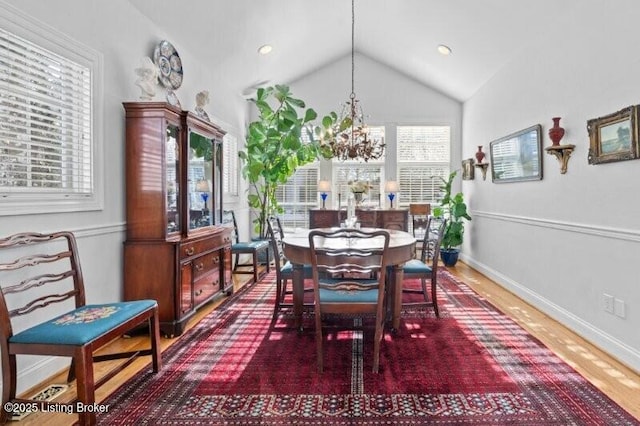 dining space with dark wood-type flooring, vaulted ceiling, a chandelier, and a healthy amount of sunlight