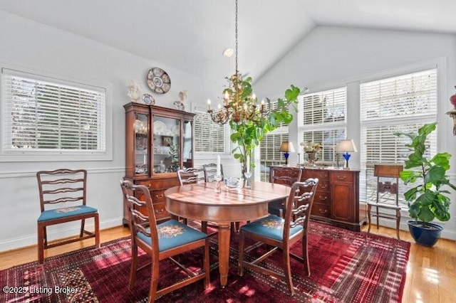 dining room featuring an inviting chandelier, lofted ceiling, wood finished floors, and a healthy amount of sunlight