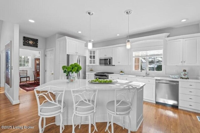 kitchen featuring appliances with stainless steel finishes, decorative light fixtures, a center island, and white cabinets