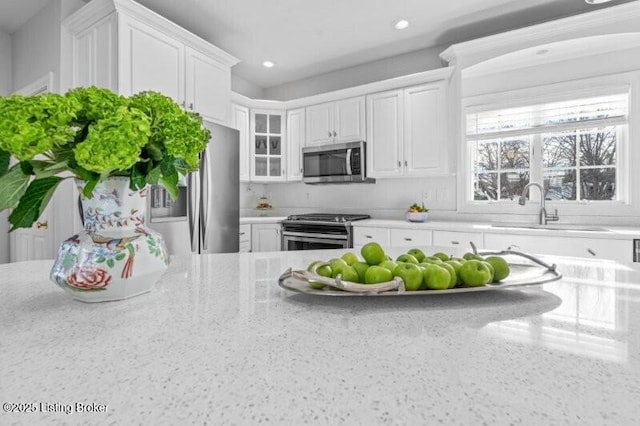 kitchen featuring sink, stainless steel appliances, white cabinets, and light stone countertops