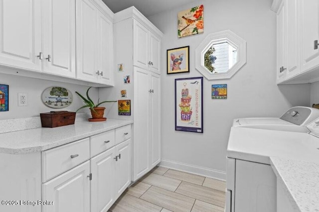 laundry room with cabinet space, washing machine and dryer, and baseboards