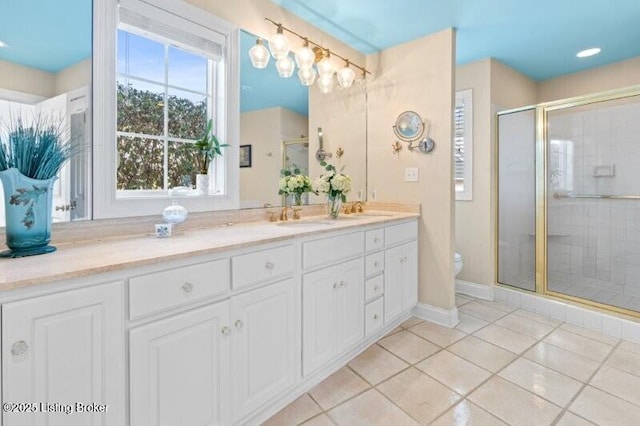 full bathroom featuring a sink, toilet, a stall shower, and double vanity