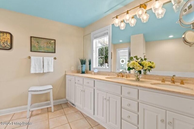 full bath featuring a sink, baseboards, double vanity, and tile patterned flooring