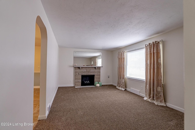 unfurnished living room with carpet, a textured ceiling, and a fireplace