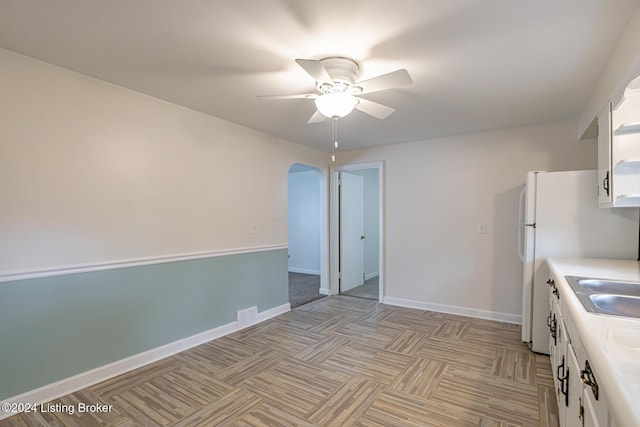 kitchen with ceiling fan, light parquet floors, and white cabinets