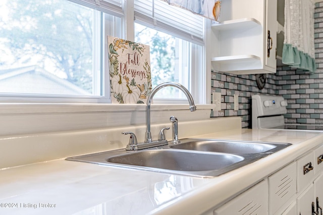 kitchen with white cabinets, a healthy amount of sunlight, tasteful backsplash, and sink