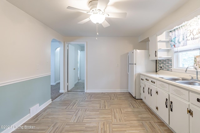 kitchen featuring ceiling fan, sink, white refrigerator, white cabinetry, and tasteful backsplash