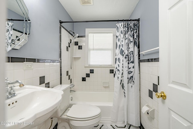 full bathroom featuring sink, tile walls, toilet, and shower / bath combo