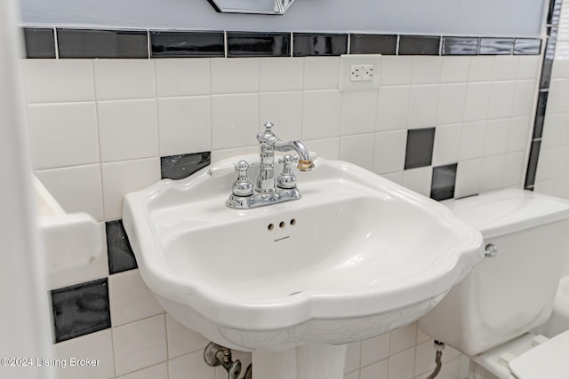 bathroom with sink, toilet, and tile walls