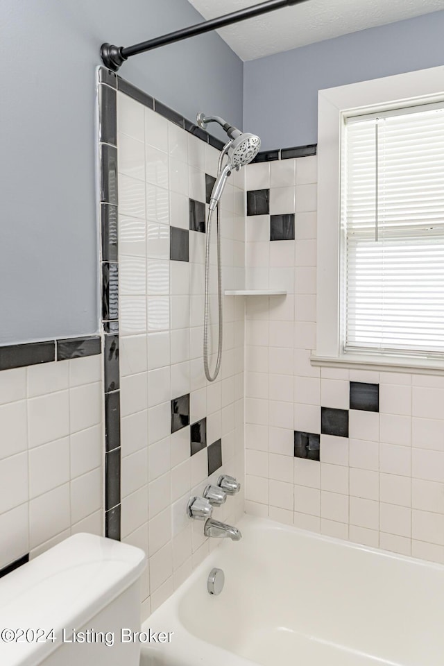 bathroom with tiled shower / bath combo and toilet