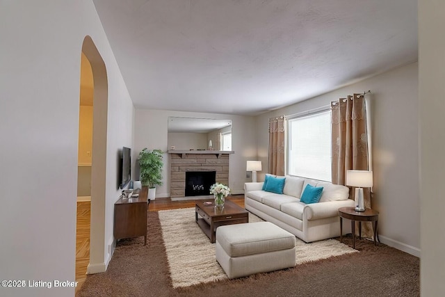 carpeted living room with a stone fireplace