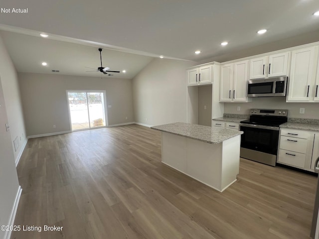 kitchen featuring light stone countertops, white cabinets, a kitchen island, light wood-type flooring, and stainless steel appliances